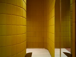A modern bathroom with yellow acoustic tiles on the walls and a minimalist design.