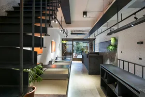 A modern coffee shop interior featuring black metal stairs and seating areas.