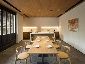 A modern dining room with wood paneling, featuring a long wooden table set for four people.