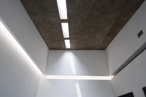 Modern interior design featuring textured concrete ceiling panels and linear lighting fixtures.