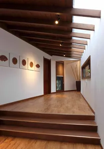 Modern interior design featuring wooden stairs and corridor with ceiling beams and artwork.