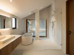 Modern minimalist bathroom with concrete floor and walls, glass shower enclosure, and freestanding bathtub.