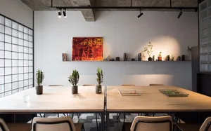 Modern office space with wooden furniture, plants, and a colorful abstract painting on the wall.