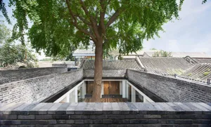Traditional Chinese architecture featuring brick walls and a central tree.