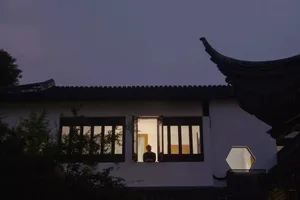 A residential exterior with white painted walls and terrazzo tile flooring during the evening.
