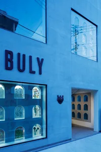 A modern storefront with a blue glass facade displaying decorative elements through arched windows.