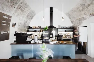 A modern coffee shop interior with concrete walls, a wooden counter, and industrial pendant lights.