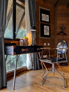 Industrial-style office space featuring a black, metallic desk frame with leather handles, a black cushioned metal chair, and