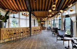 A modern restaurant bar with a wooden pine interior featuring a cozy seating area, high stools, and a polished concrete floor