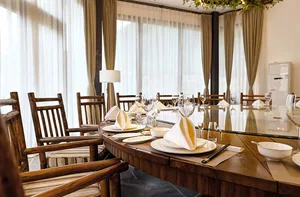 A modern restaurant dining area with a wooden table set for a meal.