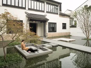 A minimalist roadside water feature constructed from concrete with a serene reflection of trees and sky.