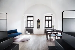 A modern living room with wooden floors, a blue sofa, and metal accents.