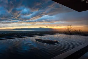 A stunning outdoor pool view during sunrise or sunset with water ripples and a picturesque landscape in the distance.