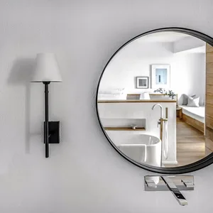 Modern minimalist bathroom featuring a round wall-mounted mirror and sleek lighting fixture.