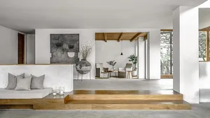 Modern minimalist living space with concrete walls and floor, featuring a cozy sitting area and a open-plan living room with 