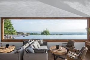 A modern living room featuring a large window with a view of the landscape, a comfortable couch, and a minimalistic design wi