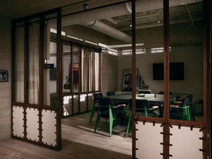 A modern industrial conference room with metal furnishings and glass windows.
