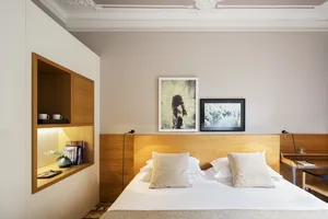 A minimalist bedroom featuring a wooden headboard and paneled walls.