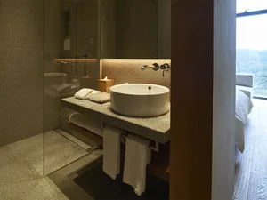 A modern residential bathroom featuring marble countertops, granite tiles on the walls, and a concrete floor.