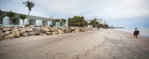 A modern beach resort with a sandy shoreline and rocky retaining wall.