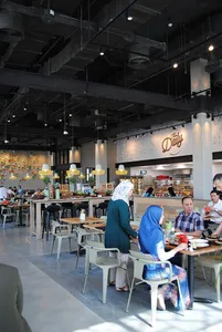 People sitting and standing in a modern cafe interior with contemporary furniture and lighting.