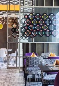 Modern cafe interior with colorful, patterned seating arrangements and decorative wall art.