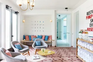 A modern spa relaxation room with ceramic tile flooring, comfortable seating, and a wall of instruction posters.