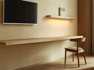 A minimalist home office featuring a wooden desk and a bookshelf with a Muji lamp on it.