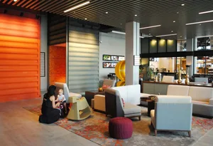A modern hotel lobby with concrete and wooden furnishings, designed with a minimalist aesthetic.