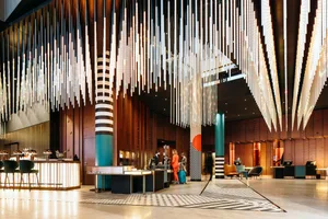 Contemporary hotel lobby featuring polished concrete flooring, wooden panels, and glass elements.