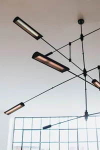 Modern industrial-style office ceiling lights hanging from metal wire framing system.