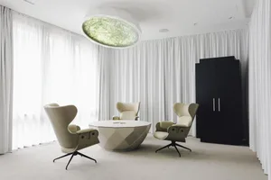 Modern living room featuring fabric and leather furniture, including three curved armchairs grouped around a geometric coffee