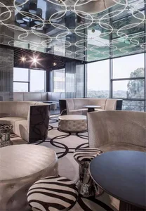 Modern lounge interior featuring fabric seating, glass tables, and metal accents.