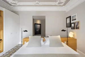 A minimalist bedroom with a large bed, white walls, and wooden headboard and nightstands.