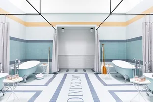 Modern public baths with blue clawfoot tubs, showers, and blue and white tiled floors.