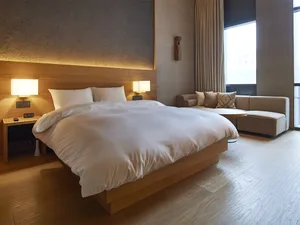 A modern bedroom with wooden furniture and a light-colored bedspread.