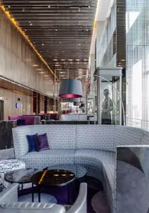 Modern restaurant and bar interior with textured cloth seating, circular tables, and contemporary lighting fixtures.