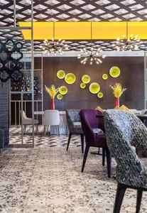 Modern restaurant interior with checkered floor, geometric ceiling pattern, and yellow decorative elements.