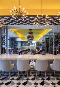 A modern restaurant interior with black and white patterned floor, contemporary lighting fixtures, and a mix of metal, glass,