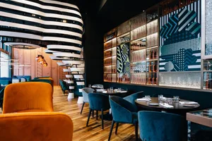 Interior of a modern restaurant featuring metal accents, glass display cases, and wooden furniture.