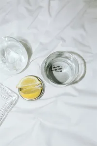 Minimalist interior space featuring a glass water glass and lemon slices on a white surface.