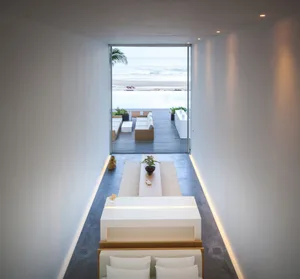 Modern beach home with concrete lounge furniture and open view of the ocean.