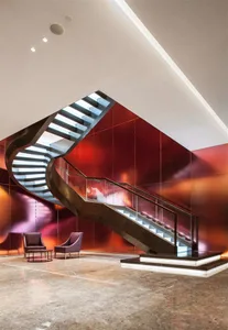 A modern industrial lobby features sleek metal and glass railings with a concrete staircase.