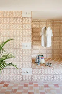 A modern laundry room with geometric patterned ceramic tile flooring and walls, featuring a clothesline and laundry basket.