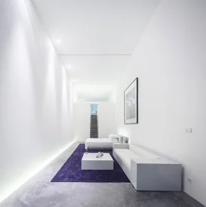 A minimalistic bedroom with concrete flooring and white furniture