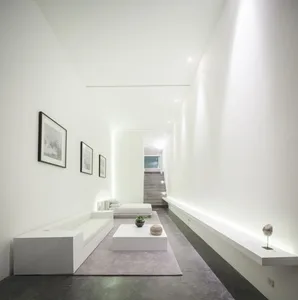 A modern minimalist living room featuring a concrete floor and walls, with white furniture and minimalist decor.