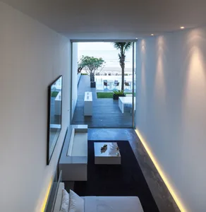 A modern residential interior featuring a concrete floor and minimalist decor, with a view of the beach through large windows