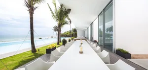 Modern seaside residence with white exterior, concrete and glass surfaces, and large windows.