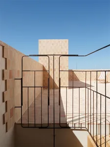 Outdoor space with a terracotta wall and concrete floor, featuring a metal gate and railing.