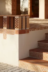Terrazzo brick staircase leading up to a building with terracotta tiles on the ground and walls